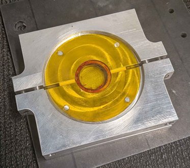 Machined aluminum glue fixture holding the bonded lens, piezo, and Kapton film