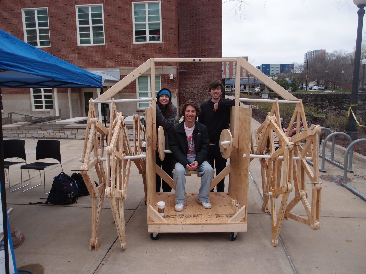 Ethan seated in the walker with two teammates at Engineering Open House